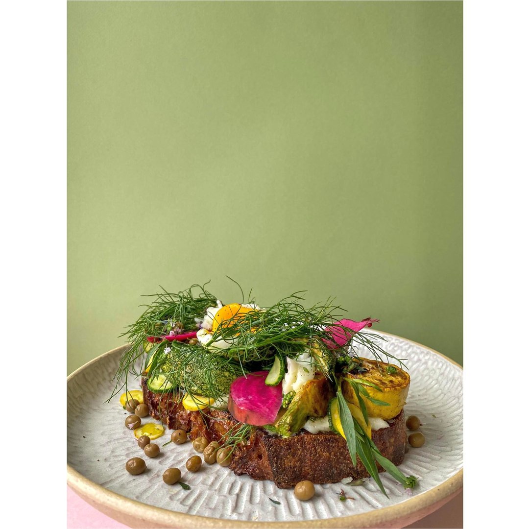 Roggensauerteigbrot mit Ziegenkäse, gebratenen Zucchini, saurer Chioggiarübe, Fenchelgrün, einem Ei, Thymianblüten und Traubenkapern.